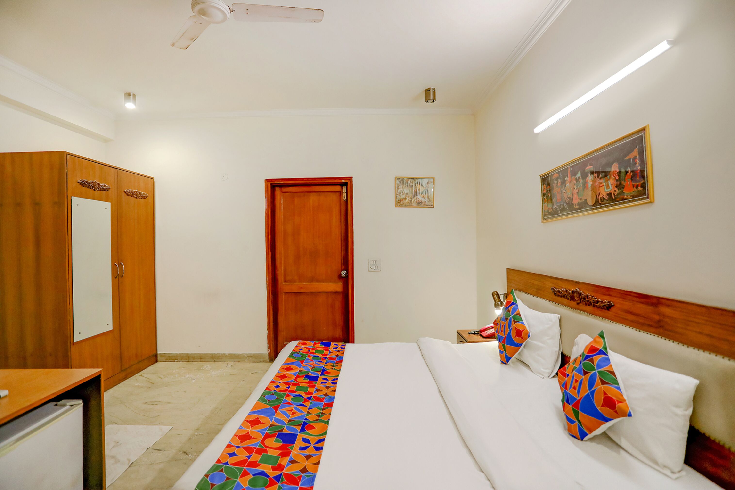 Una habitación de hotel con una cama, un armario de madera, un escritorio y una puerta.