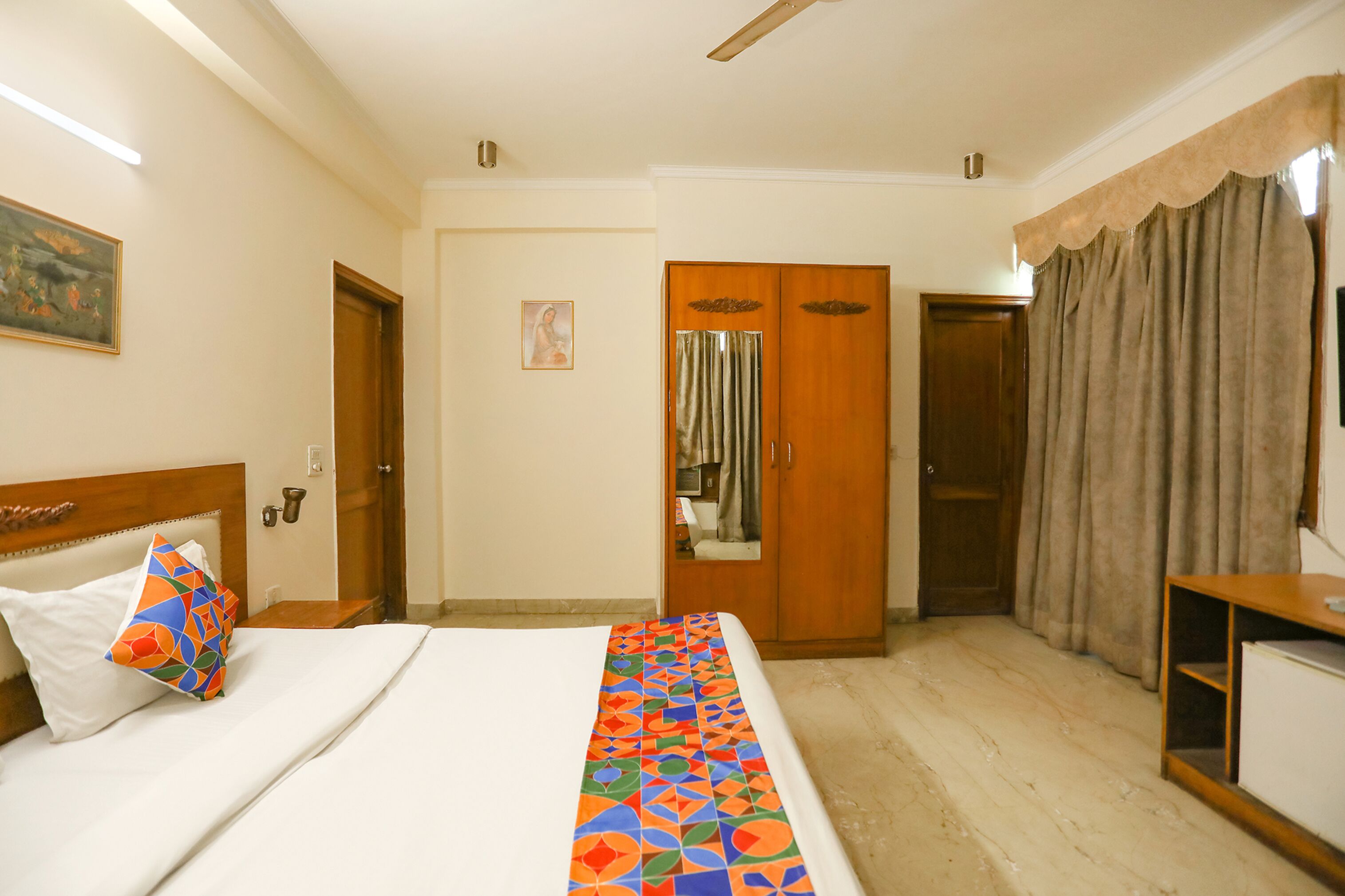 Una habitación de hotel con cama, armario, escritorio y espejo.