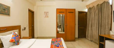 Una habitación de hotel con cama, armario, escritorio y espejo.