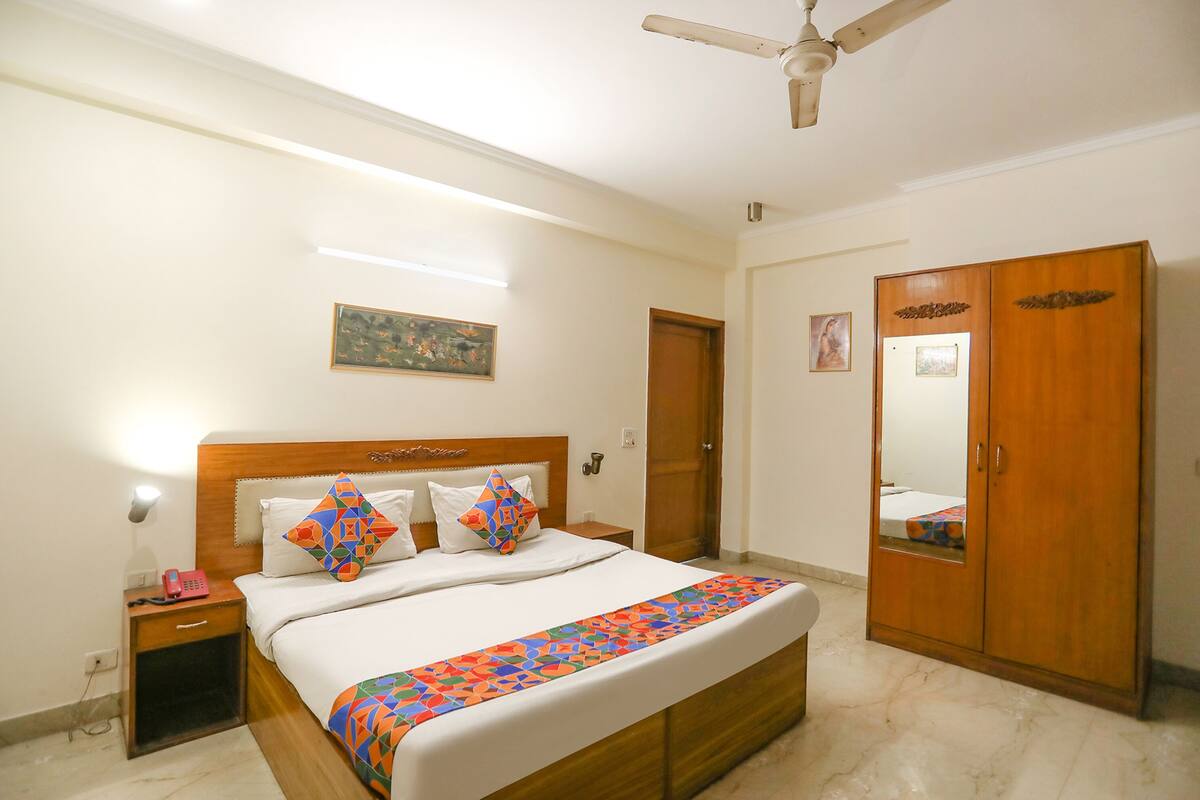 A hotel room with a bed, a wardrobe, a nightstand, and a ceiling fan.