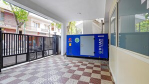 Un espace extérieur abrité avec un sol à carreaux, un distributeur automatique bleu et une clôture en métal.