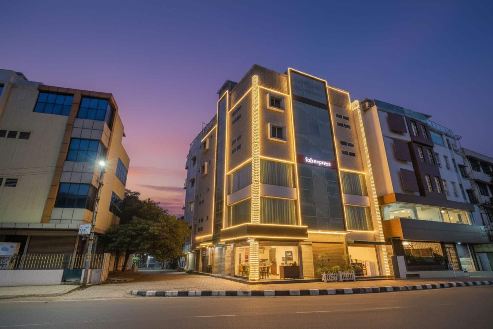 A modern hotel with a prominent 'Fabexpress' sign, a ground-floor restaurant, and a corner location with a paved street in front.