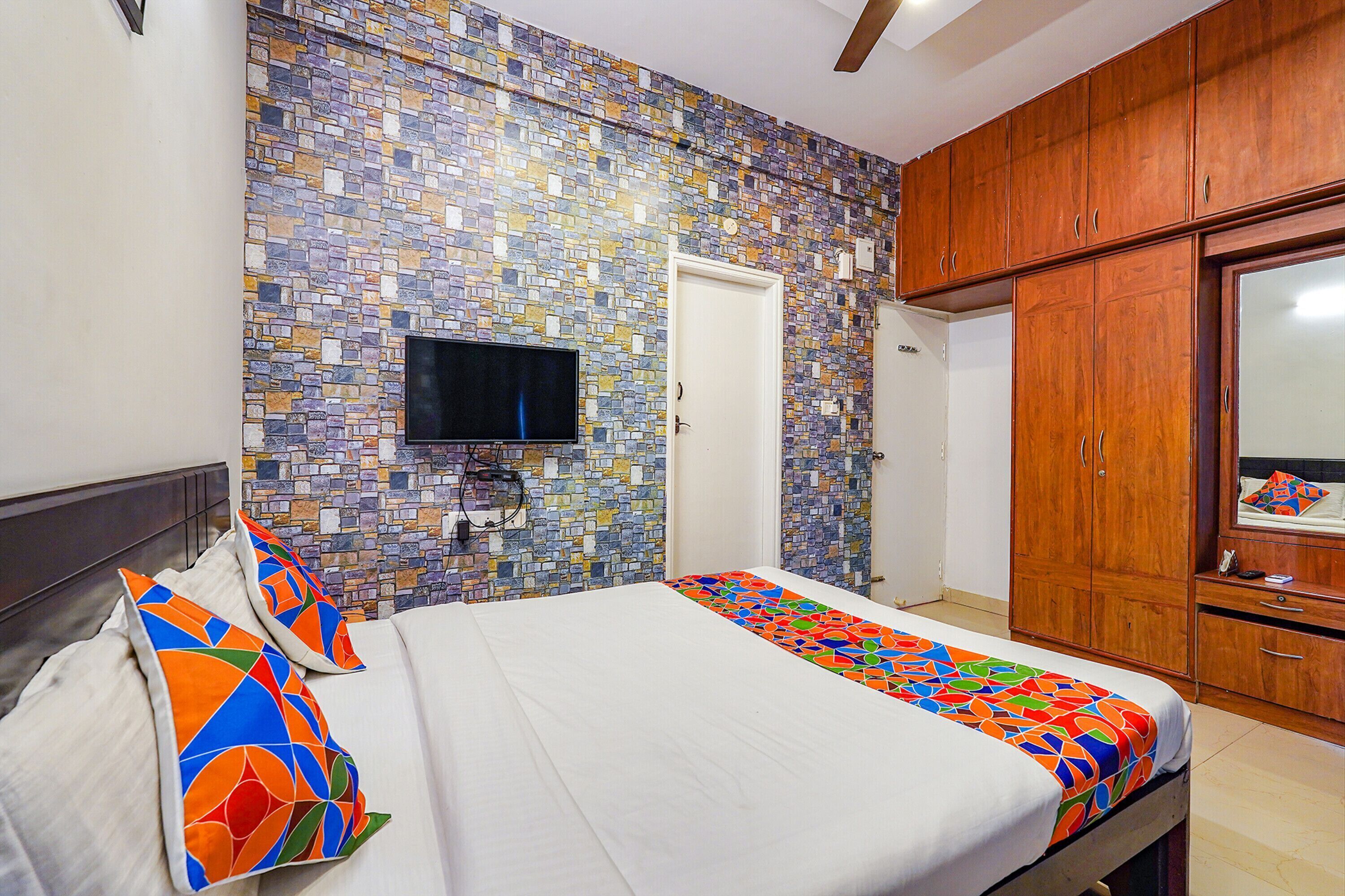 Une chambre à coucher avec un lit, un téléviseur fixé au mur et des meubles en bois.