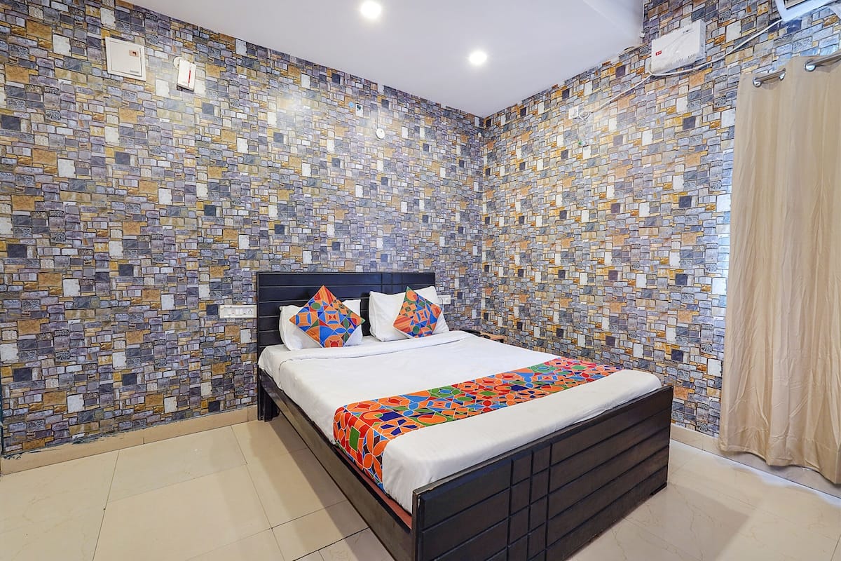 A bedroom with a bed, a patterned wall, and a curtain.