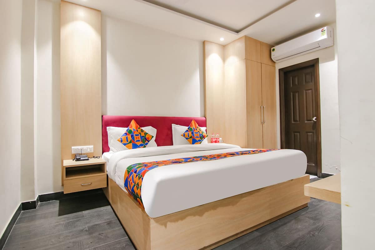 A modern hotel room with a large bed, wooden wardrobe, and an air conditioning unit.