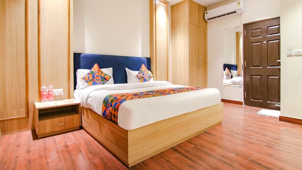 Una habitación de hotel moderna con una cama grande, un armario de madera y una mesita de noche con artículos de aseo.