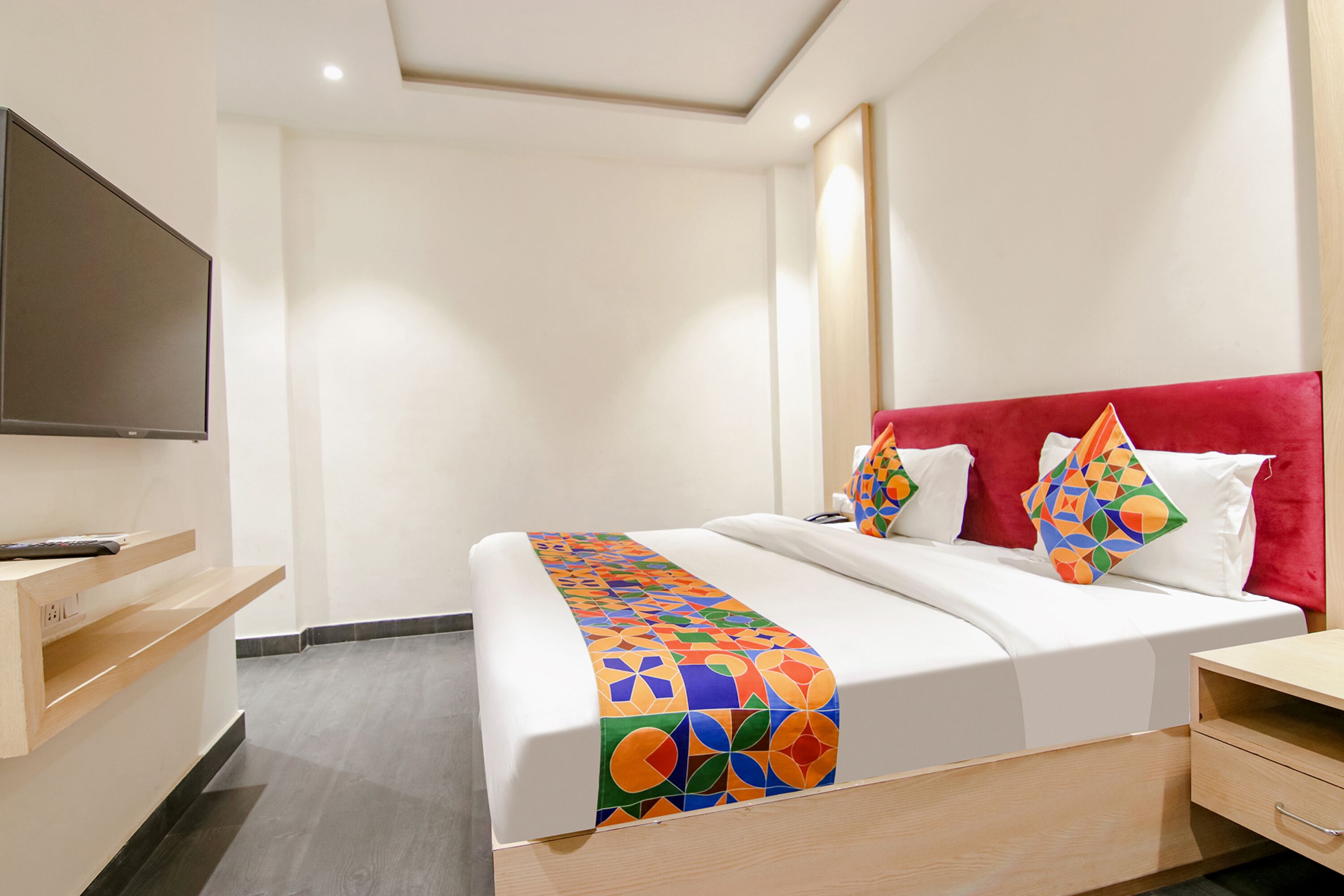 Una habitación de hotel con cama, televisor, escritorio y silla.