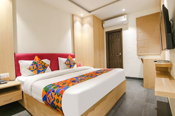 Habitación de hotel con cama, escritorio, armario y unidad de aire acondicionado.