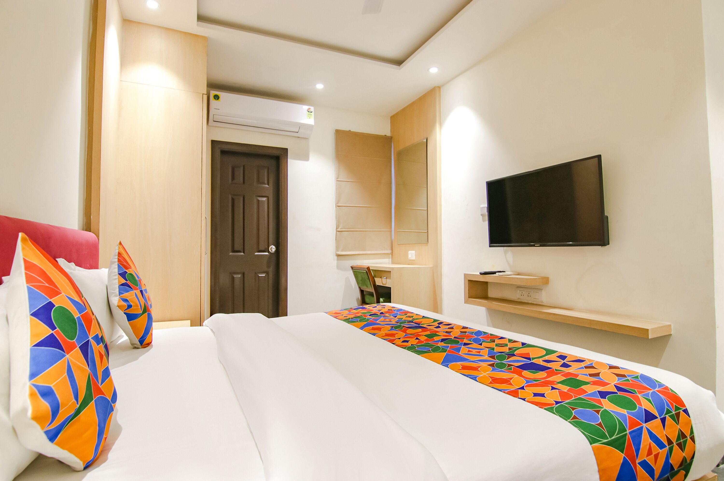 Una habitación de hotel con cama, televisión, escritorio y puerta.