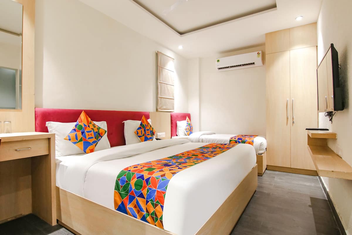 A hotel room with two beds, a desk, and a TV.