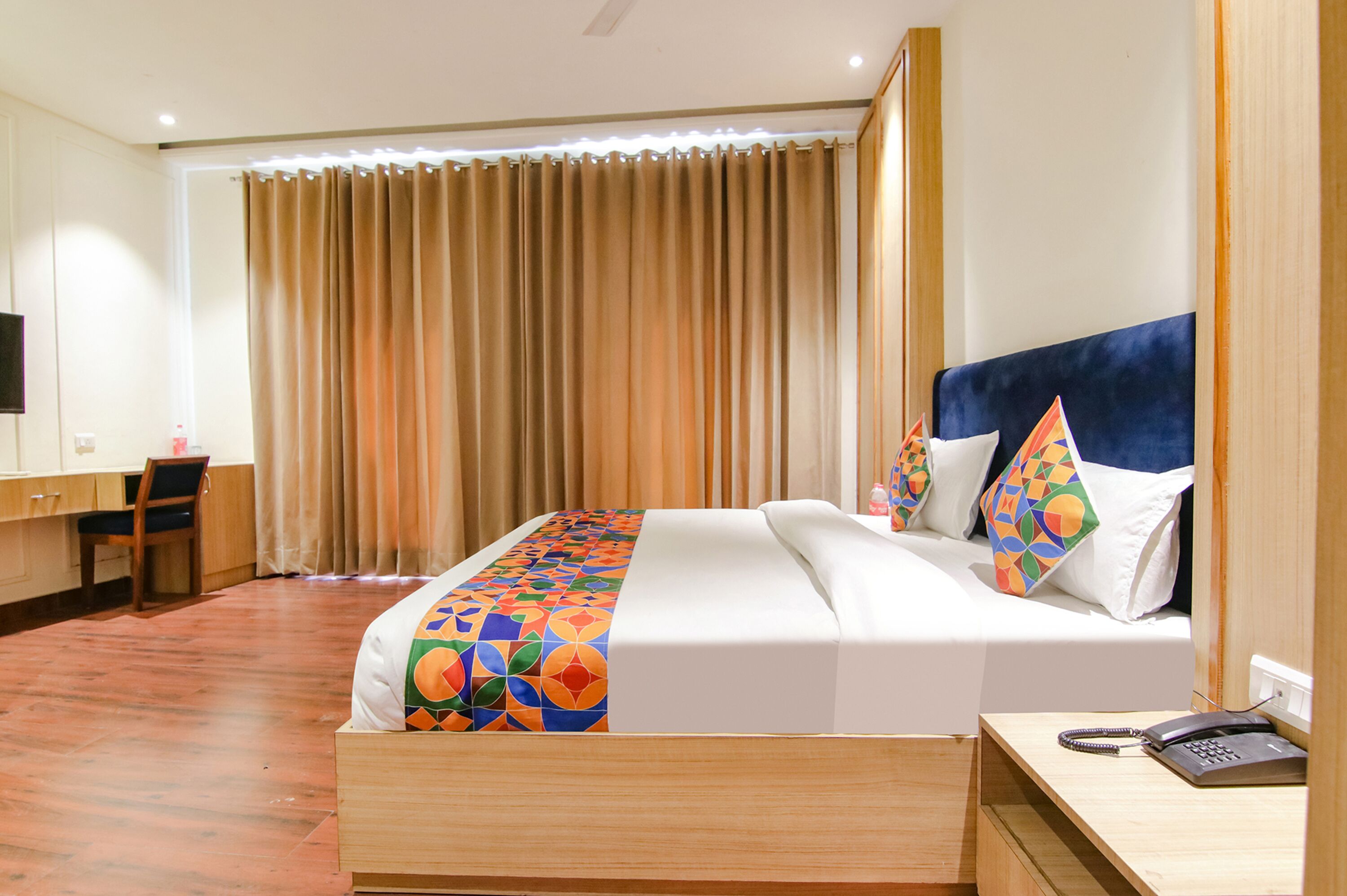 A hotel room with a bed, a desk, a chair, and a television.
