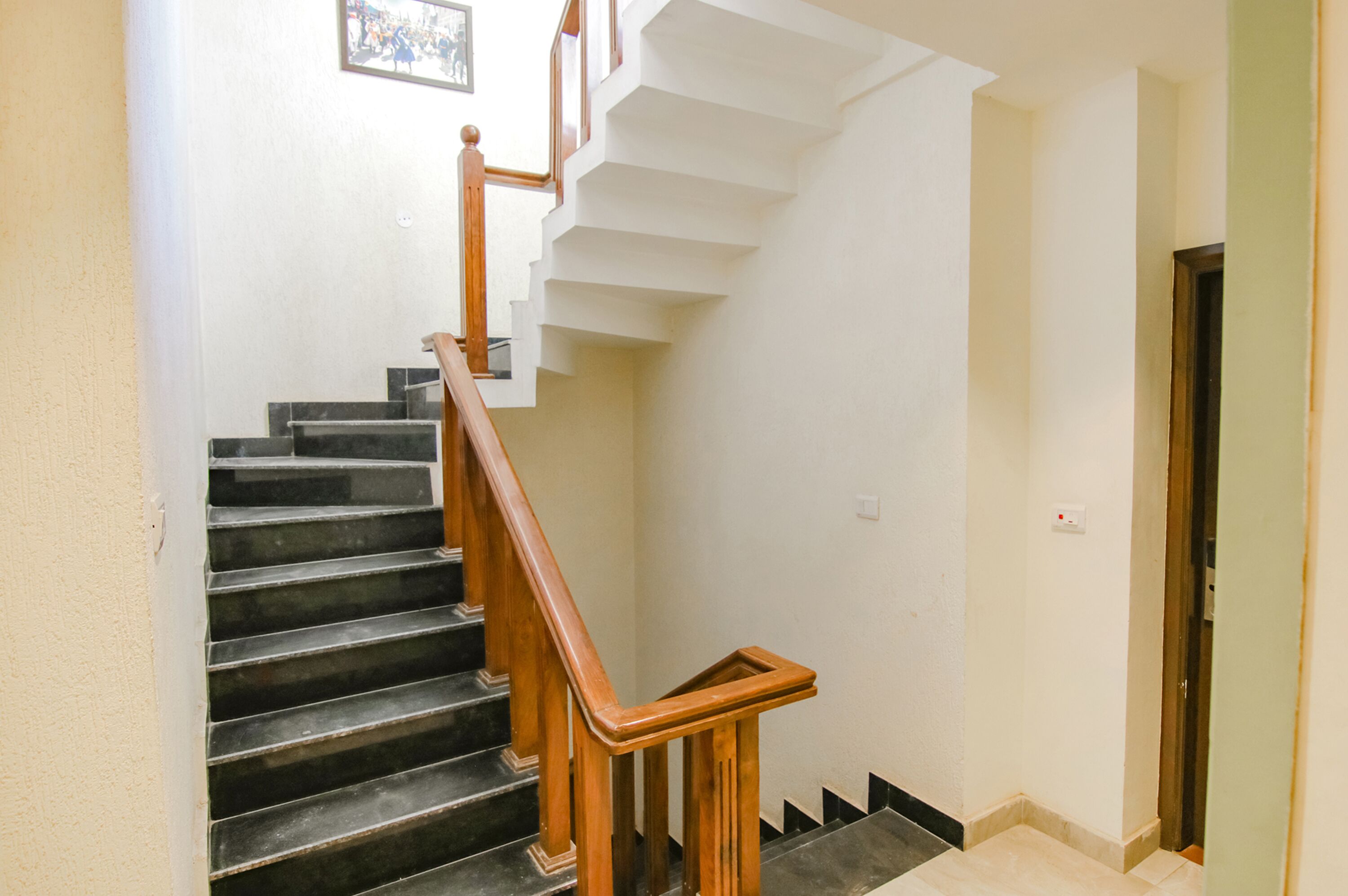 A staircase with wooden handrails and black steps leading to a landing.