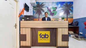 A reception desk with a 'fab hotels' logo, a TV, and a palm tree mural. - FabHotel Green Vista Malviya Nagar (Jaipur)