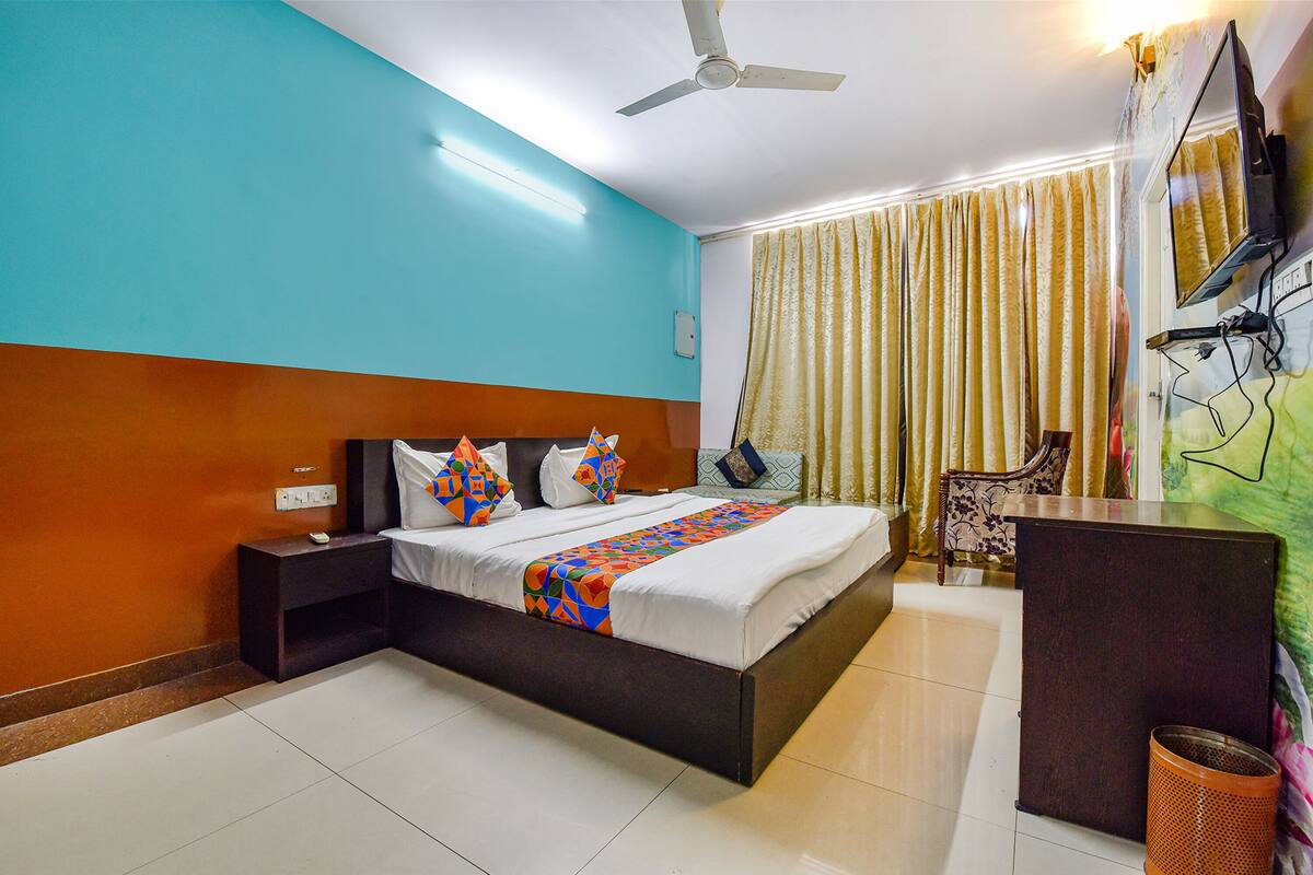 Habitación de hotel con cama, mesita de noche, escritorio y ventilador de techo.