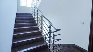 Un escalier doté d’une rampe métallique, menant à un palier avec une fenêtre.