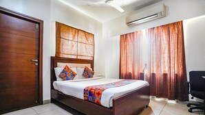 Une chambre à coucher avec un lit en bois, du linge de lit blanc, des coussins colorés, un ventilateur de plafond et un appareil de climatisation.