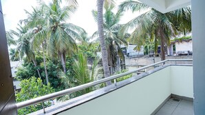Un balcon doté d’une rambarde en métal, donnant sur un jardin planté de palmiers.