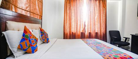 Une chambre d’hôtel avec un grand lit, une tête de lit, un climatiseur, un bureau et une chaise.