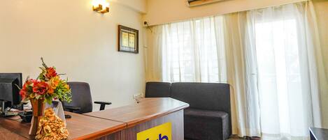 A reception desk with a logo, a sofa, a TV, and a window with curtains.