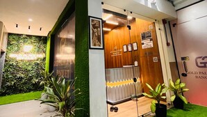 Entrada de hotel con un muro verde, un mostrador de recepción de madera y un cartel que indica prohibido fumar.
