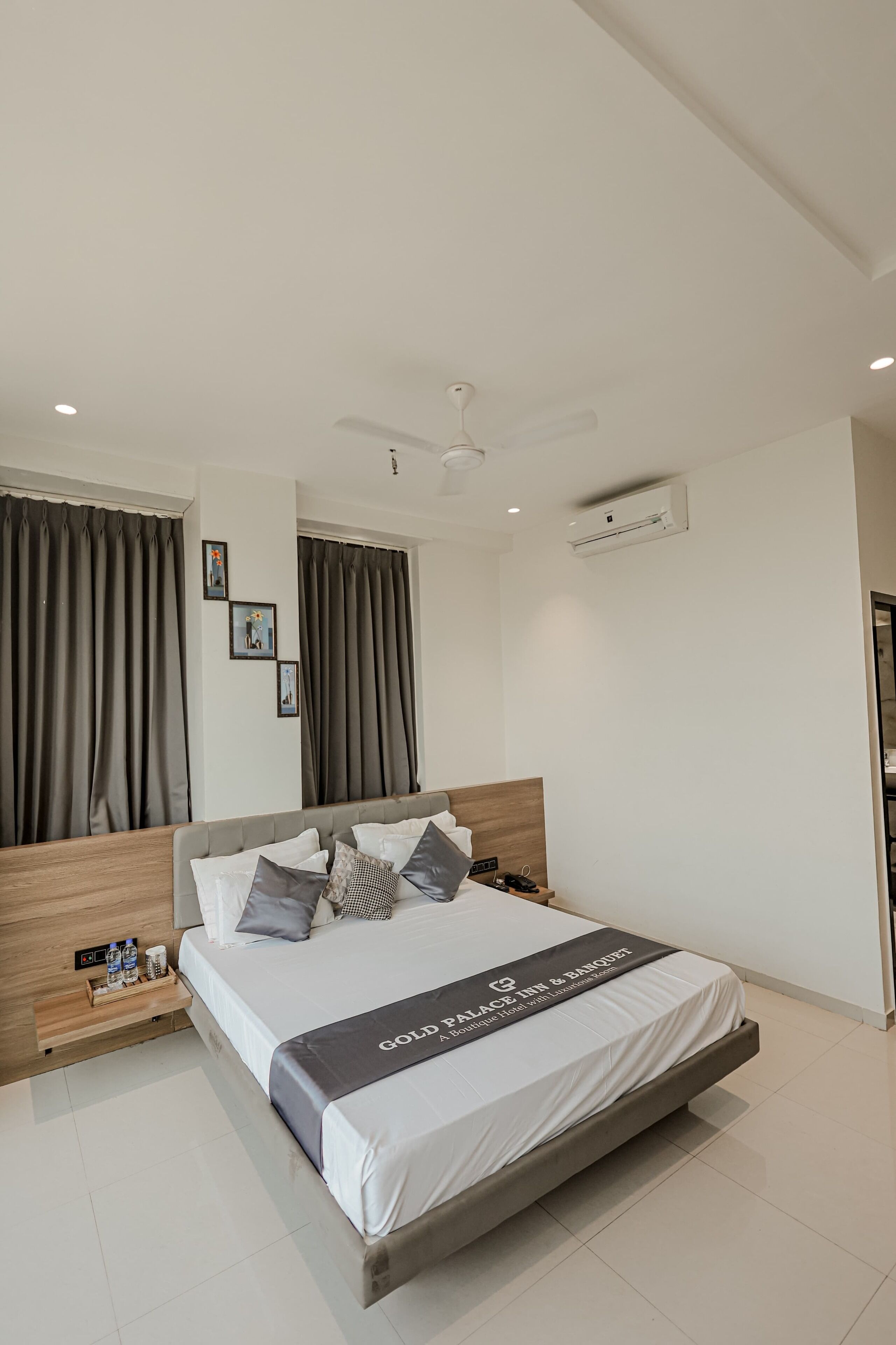 A modern hotel room with a large bed, a ceiling fan, and an air conditioning unit.