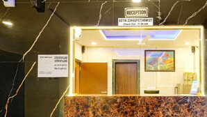 Zona de recepción con mostrador de mármol, ventilador de techo y señalización de salida.
