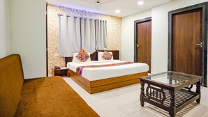 Un dormitorio con cama, una mesa de vidrio, un sofá marrón y una puerta de madera.