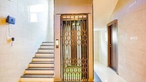 Una escalera que lleva a una habitación con una reja de metal, una luz fijada en la pared y una puerta.