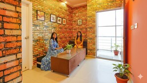 A room with a brick wall, a reception desk, and two people seated. - FabHotel Kings Suites Banaswadi (Bengaluru)