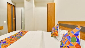 Habitación de hotel con una cama, cabecera de madera y corredor de cama colorido.