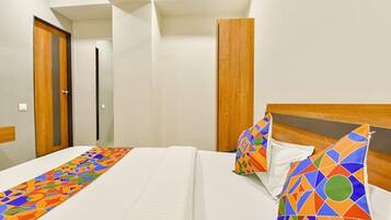 Habitación de hotel con una cama, cabecera de madera y corredor de cama colorido.