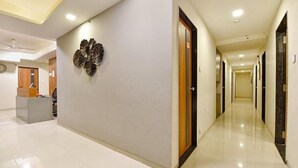 Pasillo de hotel con una recepción, un elemento decorativo en la pared y varias puertas.