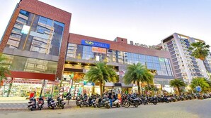 Un hotel con fachada de vidrio moderna, un cartel que dice 'Fab Hotels' y una fila de motocicletas estacionadas al frente.