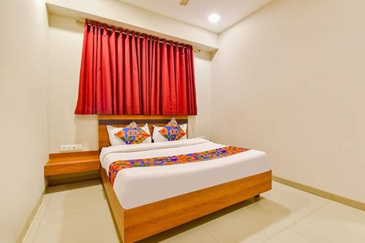 A bedroom with a wooden bed, red curtains, and colorful pillows.