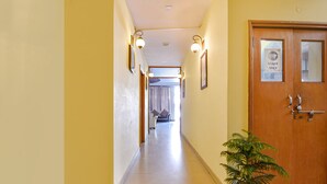 Un pasillo de hotel con una puerta de madera que dice 'STOP STAFF ONLY', una planta en maceta y vistas a una habitación con cama y cortinas.