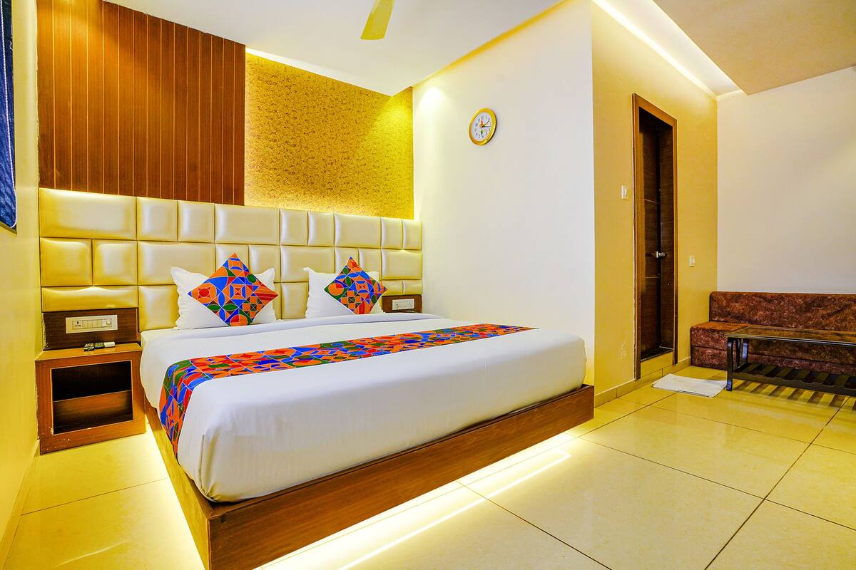 Habitación de hotel con una cama grande, cabecera de madera, mesita de noche y un sofá.