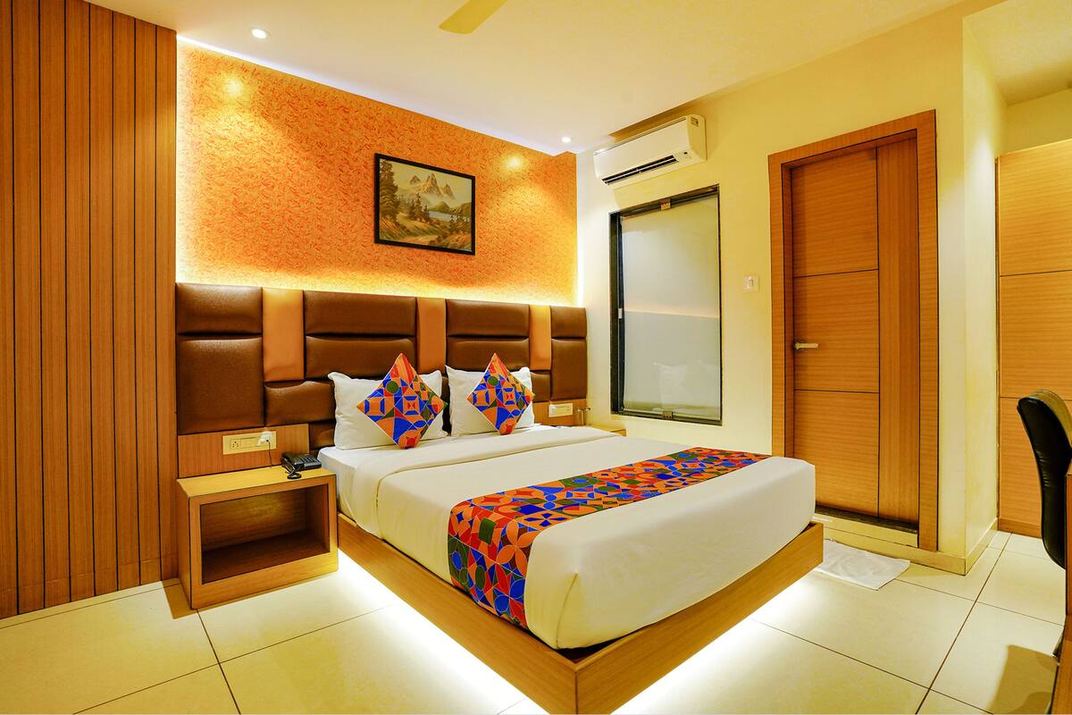 Una habitación de hotel moderna con una cama grande, cabecera de madera y un cuadro en la pared.