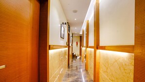 Un pasillo con paneles de madera y suelo de mármol, que conduce a una escalera.