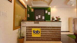 Una recepción con un letrero de 'fab hotels', un ventilador de techo y una planta en maceta.
