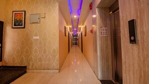 Un pasillo de hotel con papel tapiz estampado, un cuadro enmarcado, un ascensor y un letrero que dice 'Sky Touch'.