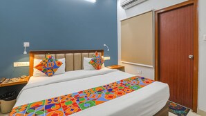Habitación de hotel con cama, mesita de noche, aire acondicionado de pared y puerta de madera.