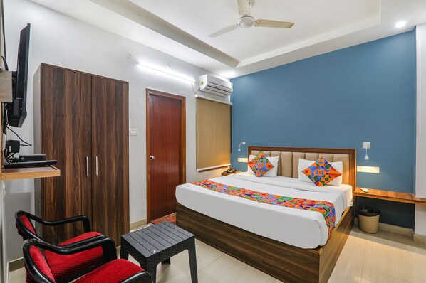 Quarto de hotel com uma cama, uma escrivaninha, uma cadeira e um ar condicionado.