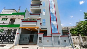 Un hotel moderno con una llamativa fachada de vidrio vertical, varios balcones y un cielo azul claro al fondo.