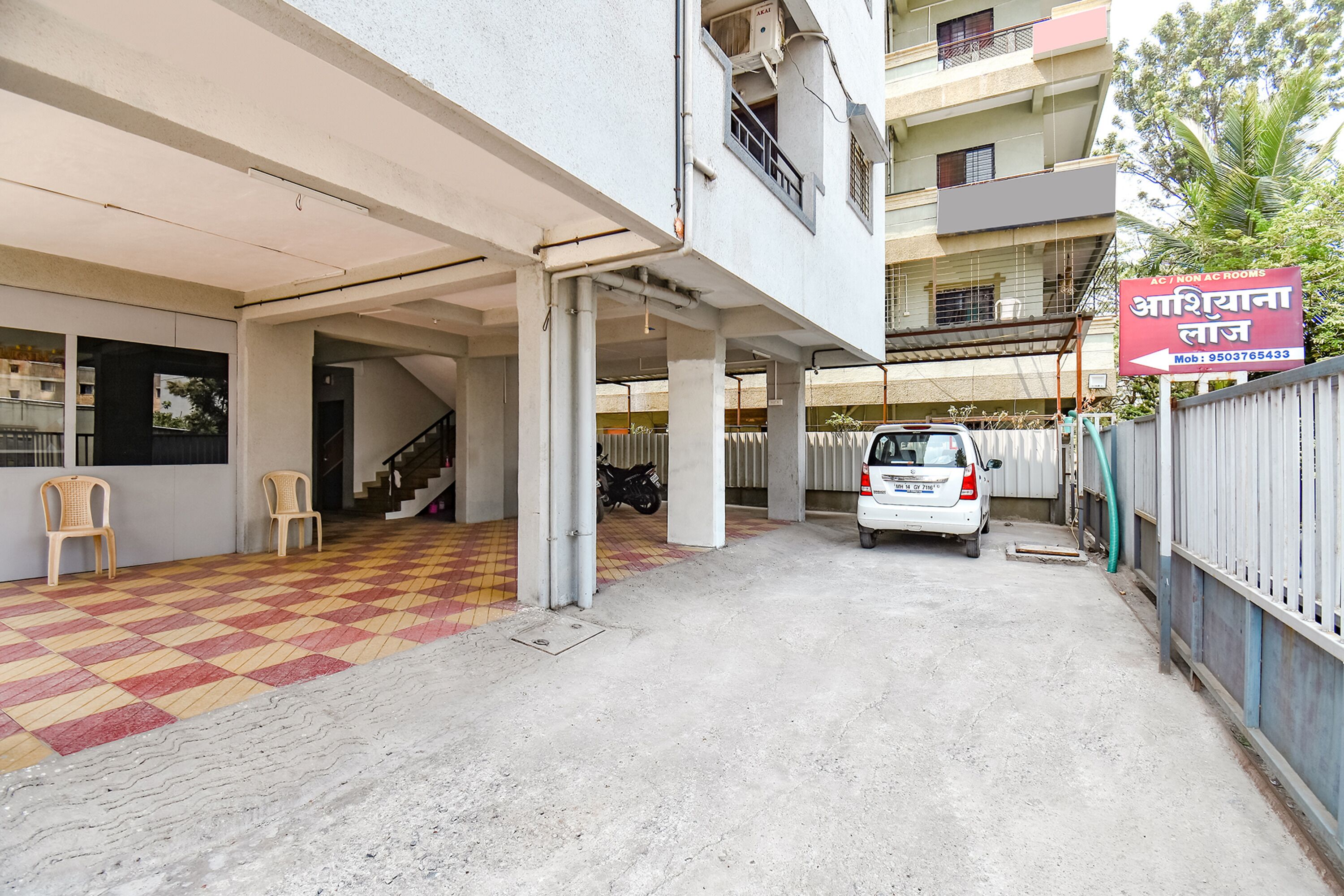 A building with a checkered floor, a white car parked in front, and a sign in a foreign language.