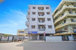A multi-story hotel with a prominent 'fab hotels' sign, a gated entrance, and a clear blue sky.