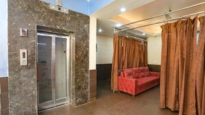 Un vestíbulo de hotel con una pared de mármol, un sofá rojo y una cortina.