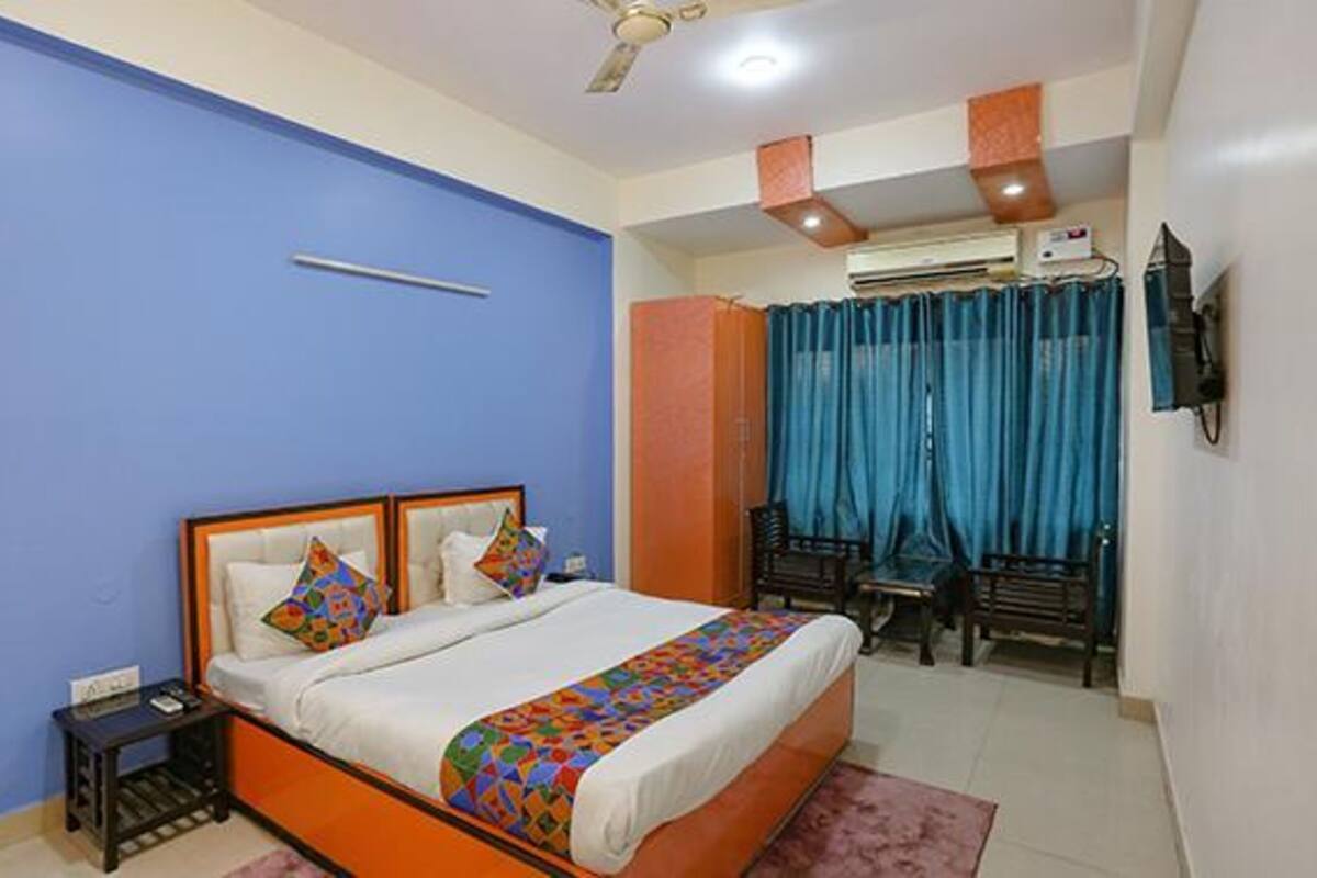 A bedroom with a bed, a nightstand, a ceiling fan, and a window with curtains.