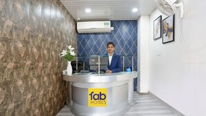A reception desk with a 'fab hotels' sign, a wall-mounted air conditioner, and framed artwork on the wall. - FabHotel Veetara (New Delhi)