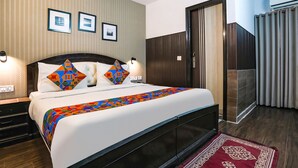 A hotel room with a large bed, two bedside tables, a wardrobe, and a red carpet. - FabHotel Veetara (New Delhi)