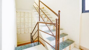 Una escalera con barandilla de madera y peldaños de mármol.